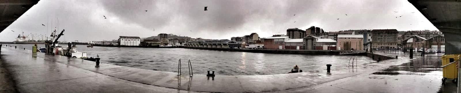 Vista panorámica do porto de Ribeira baixo a choiva, cos barcos amarrados no peirao